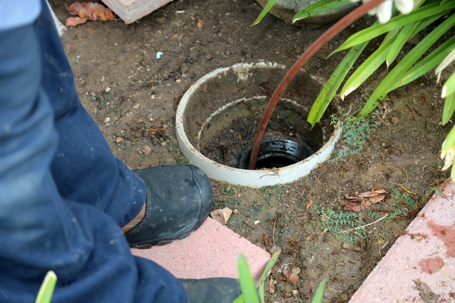 Sewer cleaning. A plumber uses a sewer snake to clean blockage in a sewer line.