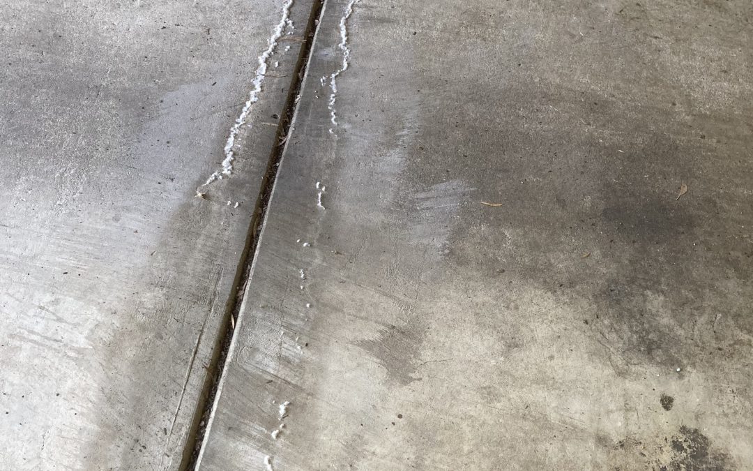 White residue appearing on a concrete garage floor caused by a hidden water leak in Eltham