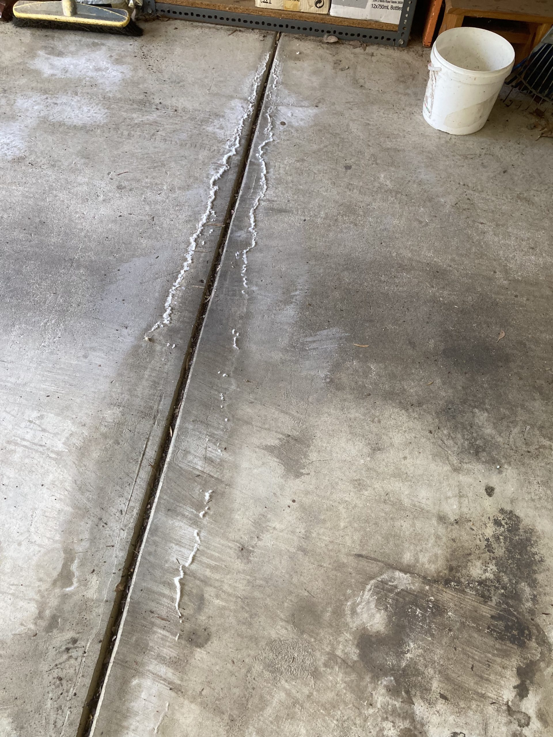 White residue appearing on a concrete garage floor caused by a hidden water leak in Eltham