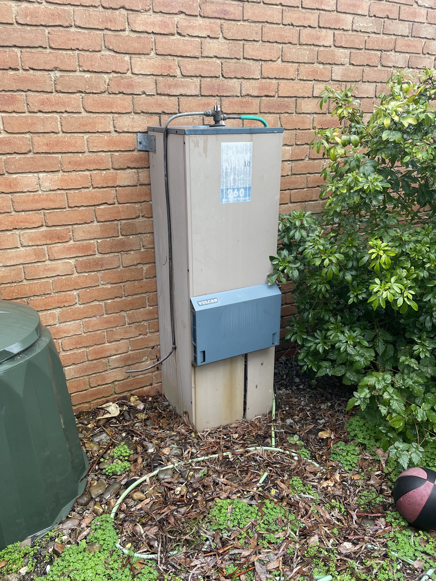 Old gas hot water system outside a Melbourne home showing an ageing hot water unit