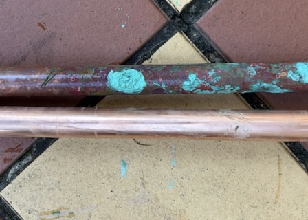 Corroed vs New Copper Water Pipe Corroded copper water pipe next to a new copper pipe, showing pipework that may need replacing