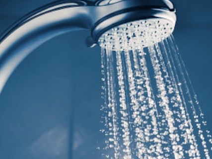 Filtered water running from a shower head with a whole-house water filter
